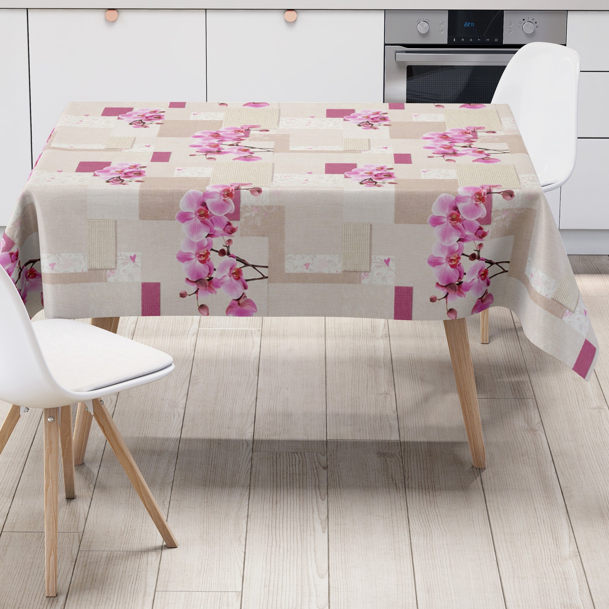 Rechteckiges Wachstuch mit hellem Beige- und Cremeton als Hintergrund, dekoriert mit großen rosa Orchideenblüten, pinkfarbenen Akzenten und einem modernen Patchwork-Muster aus Quadraten, Rechtecken und dezenten floralen Ornamenten. Die Tischdecke wirkt freundlich, elegant und romantisch.