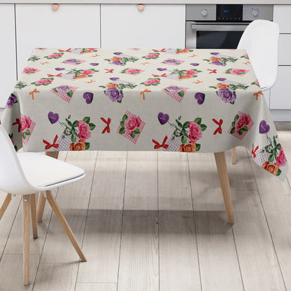 Rechteckige Wachstuch-Tischdecke mit romantischem Blumenmuster auf cremefarbenem Hintergrund. Rosa, lilafarbene und apricotfarbene Rosen wechseln sich mit grünen Blättern, karierten rosa Elementen, kleinen Schleifen und lilafarbenen Herzen mit „Love“-Aufschrift ab. Die Tischdecke fällt dekorativ über die Tischkanten und vermittelt einen verspielten, floralen Landhausstil.