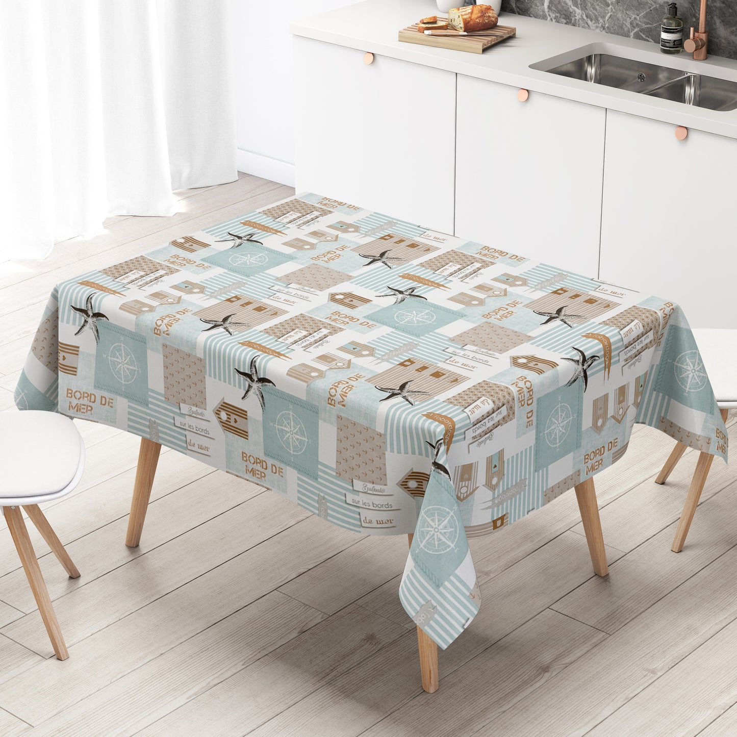 Maritime Wachstuch-Tischdecke mit Patchwork-Muster in Türkis, Beige und Weiß, verziert mit Strandhäusern, Seesternen, Kompassrosen, Streifen und dekorativen Schriftzügen im Küstenstil.