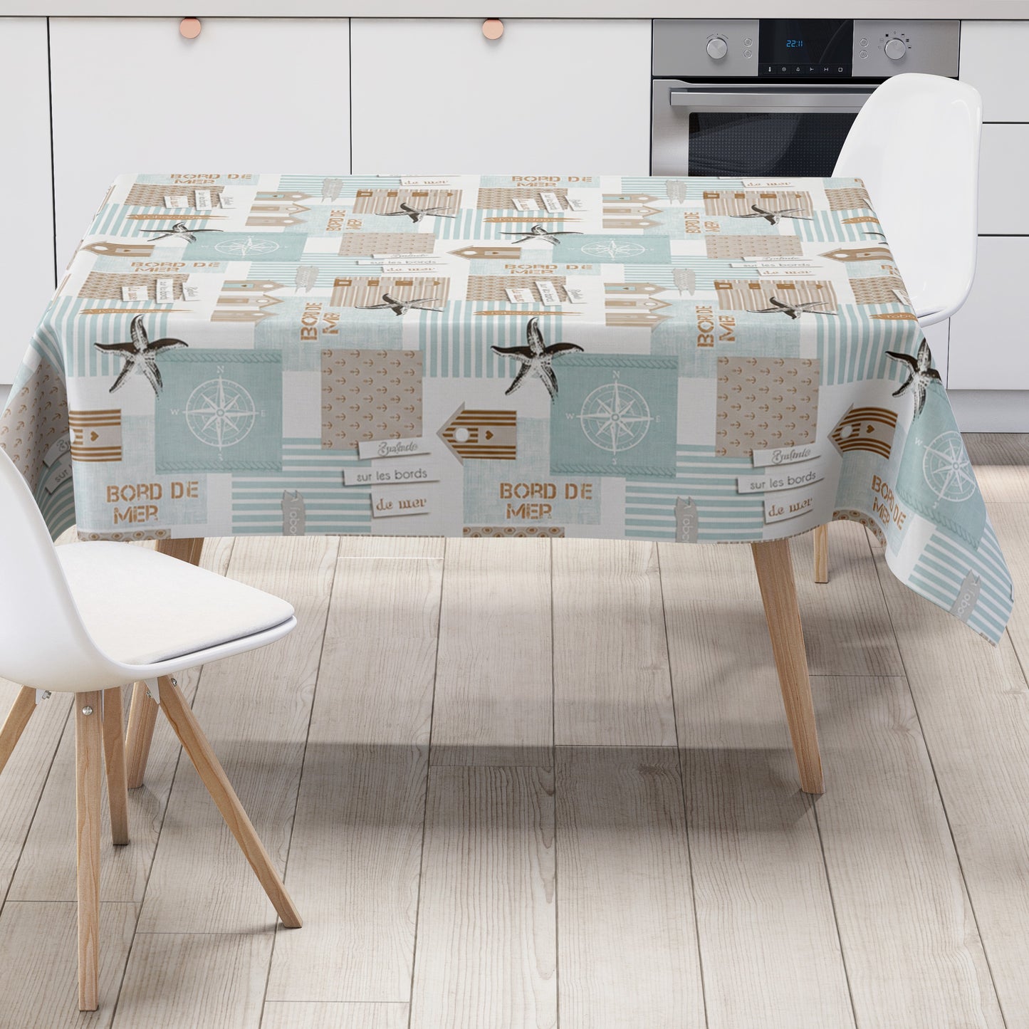 Maritime Wachstuch-Tischdecke mit Patchwork-Muster in Türkis, Beige und Weiß, verziert mit Strandhäusern, Seesternen, Kompassrosen, Streifen und dekorativen Schriftzügen im Küstenstil.