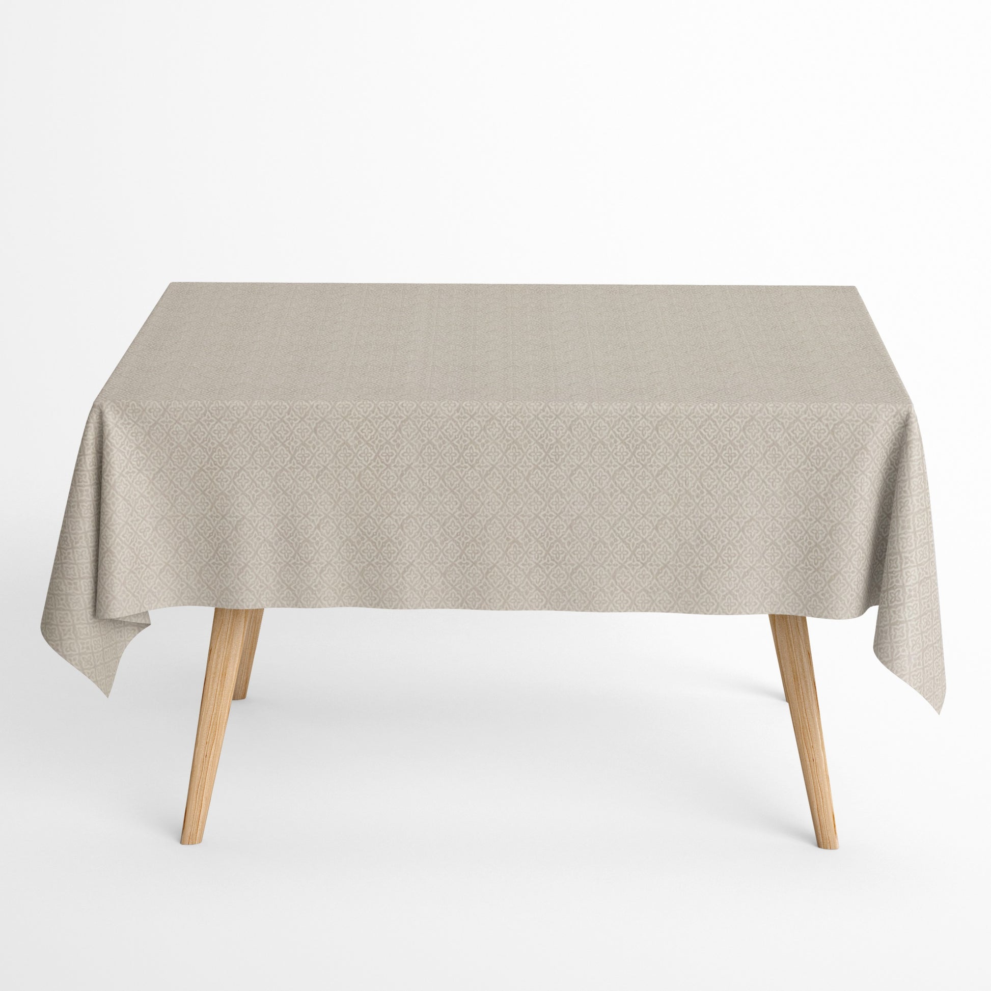 Jacquard-Tischdecke aus beschichteter Baumwolle mit Fleckenschutz, beige mit filigranem Rauten- und Blumenmuster, auf einem Holztisch drapiert.