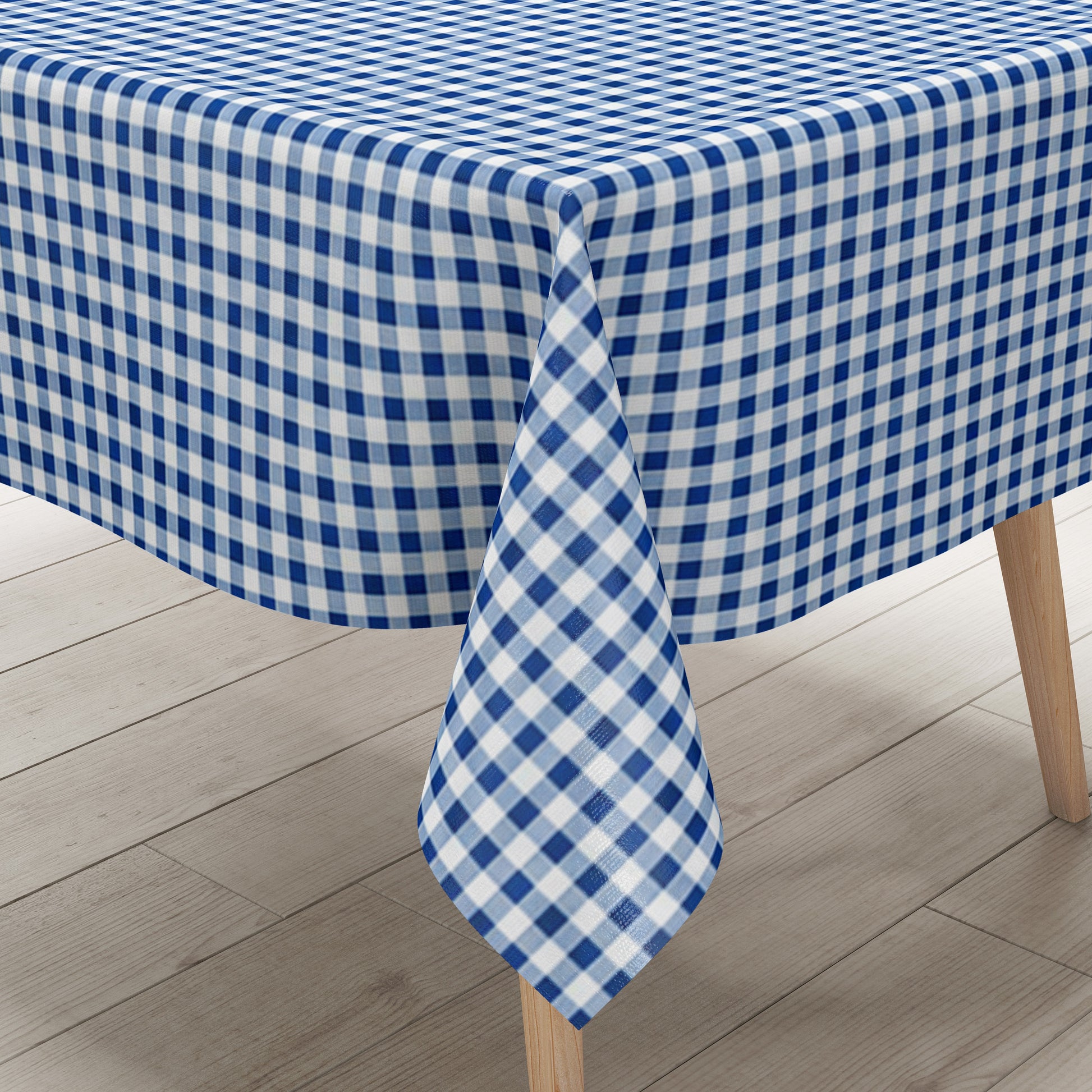 Blau-weiß karierte Wachstuch-Tischdecke in Nahaufnahme. Das feine Vichy-Karomuster besteht aus gleichmäßigen kleinen Quadraten und verläuft glatt und eben über die gesamte Fläche. Die Oberfläche wirkt faltenfrei und gleichmäßig ausgeleuchtet.