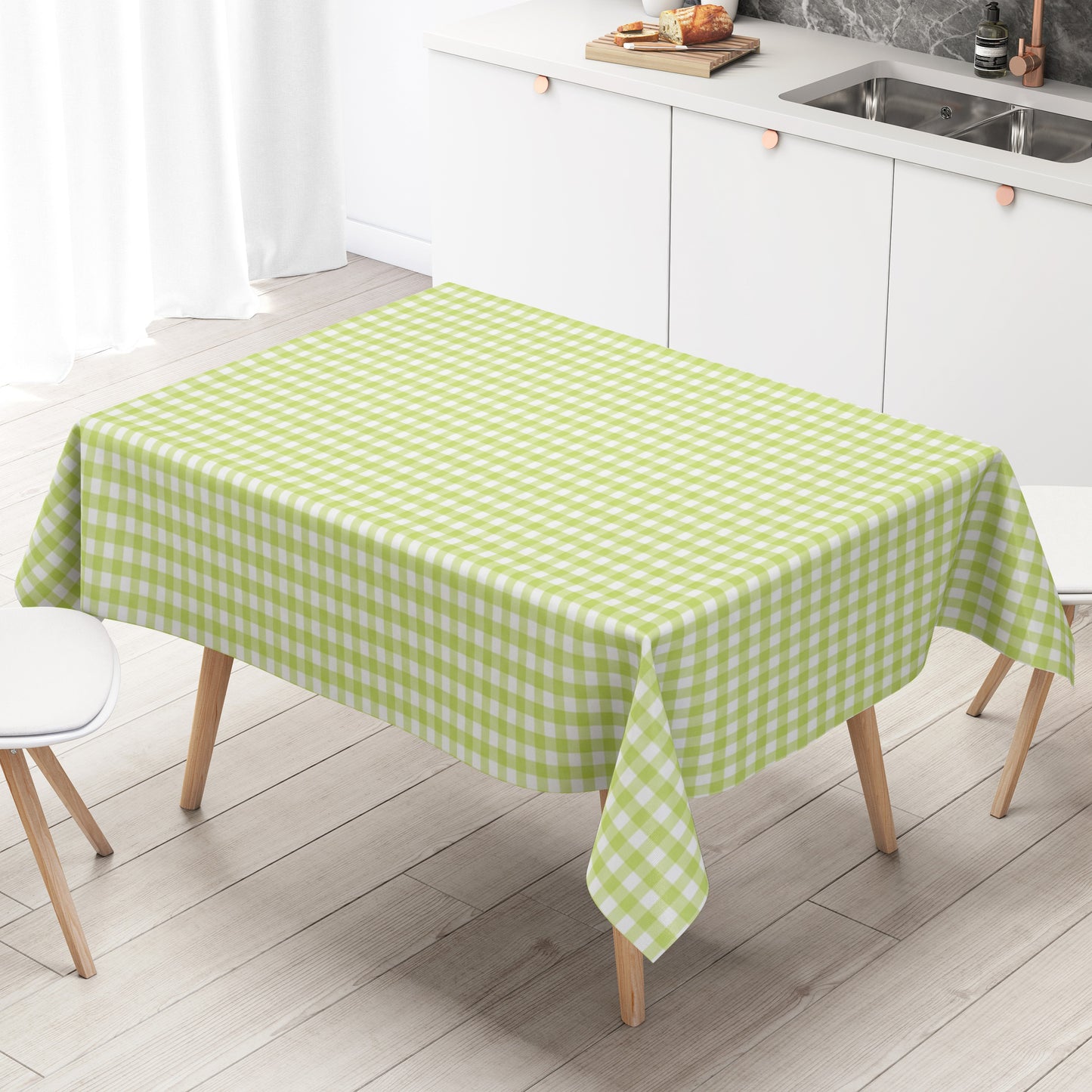 Hellgrün-weiß karierte Wachstuch-Tischdecke mit klassischem Vichy-Karomuster über einer Tischecke. Die abwischbare, wasserabweisende Tischdecke fällt gleichmäßig über die Kanten und liegt auf einem Holztisch in einer modernen Küche.