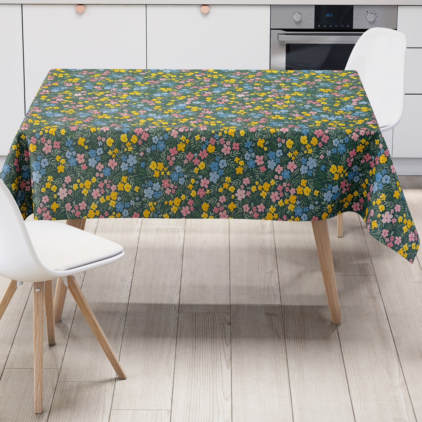 Dunkelgrüne Wachstuch-Tischdecke mit buntem Streublumenmuster aus kleinen gelben, rosa und blauen Blüten sowie feinen grünen Blättern, die über die gesamte Oberfläche verteilt sind.