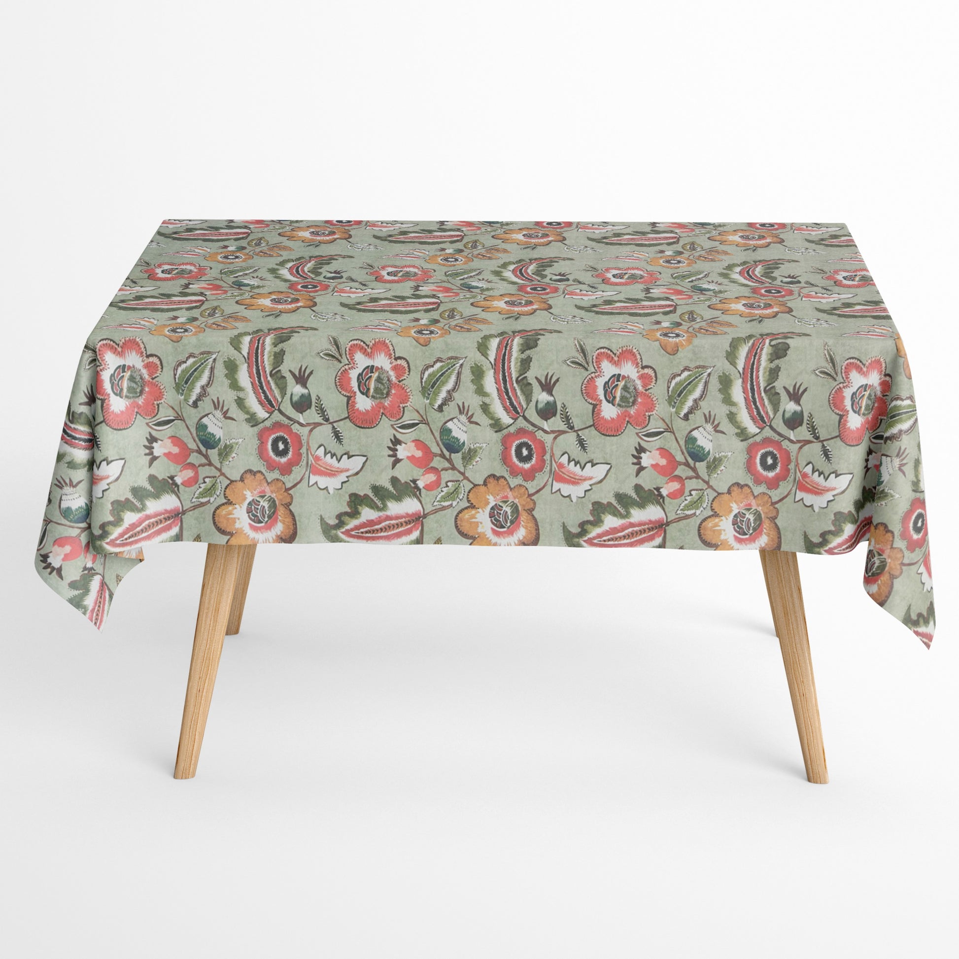 Beschichtete Baumwoll-Tischdecke mit floralem Muster auf olivgrünem Hintergrund, verziert mit großen Blüten in Korall-, Orange- und Cremetönen sowie dekorativen Blättern. Über eine Tischecke drapiert, mit sichtbaren hellen Holzbeinen.