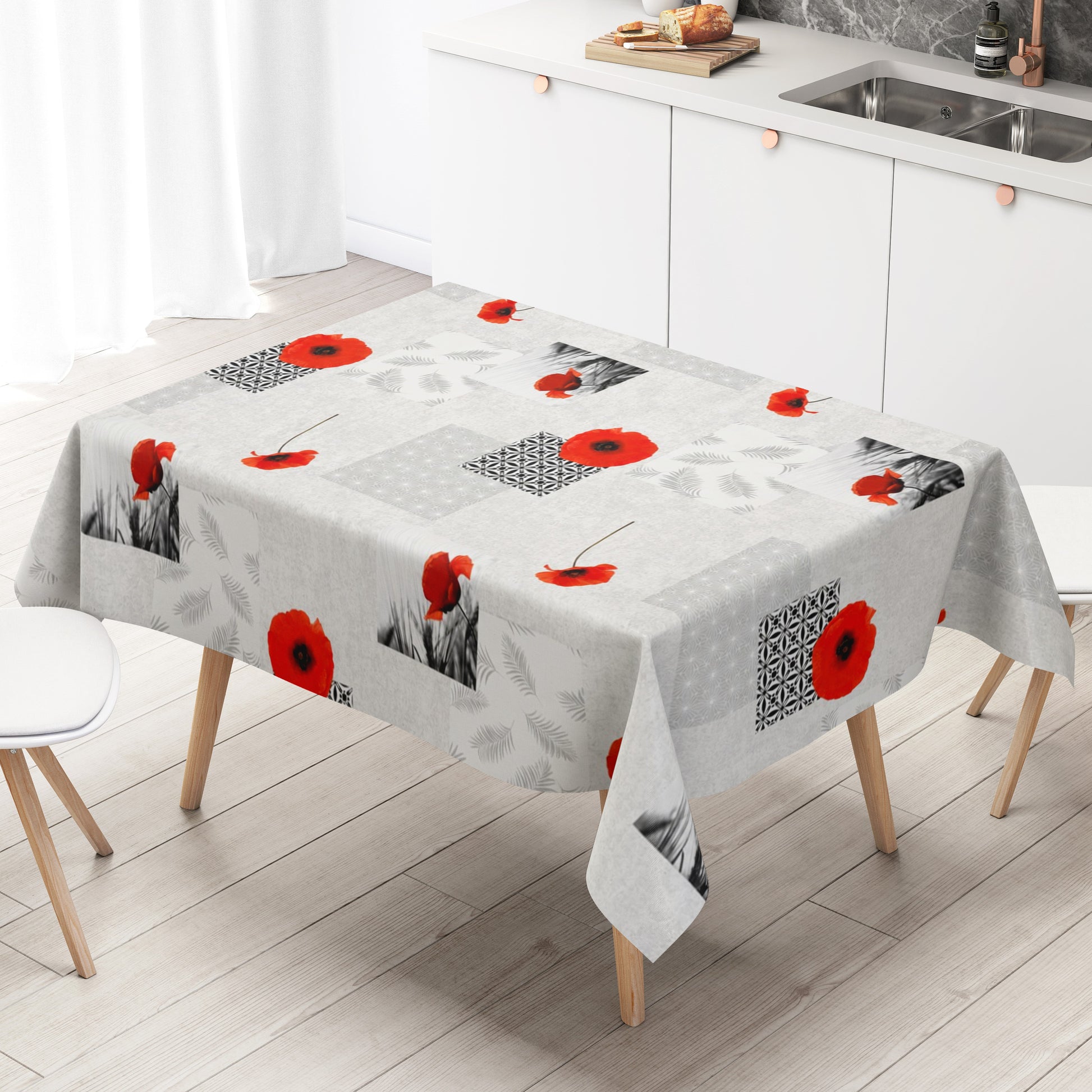 Wachstuch-Tischdecke mit modernem Mohnblumen-Motiv auf hellem Hintergrund. Das Design kombiniert leuchtend rote Mohnblüten mit geometrischen Mustern, filigranen Blattmotiven und dekorativen Schwarz-Weiß-Fotoelementen im Patchwork-Stil. Die wasserabweisende Tischdecke fällt gleichmäßig über die Kanten eines rechteckigen Tisches und ist vor weißem Hintergrund freigestellt dargestellt.