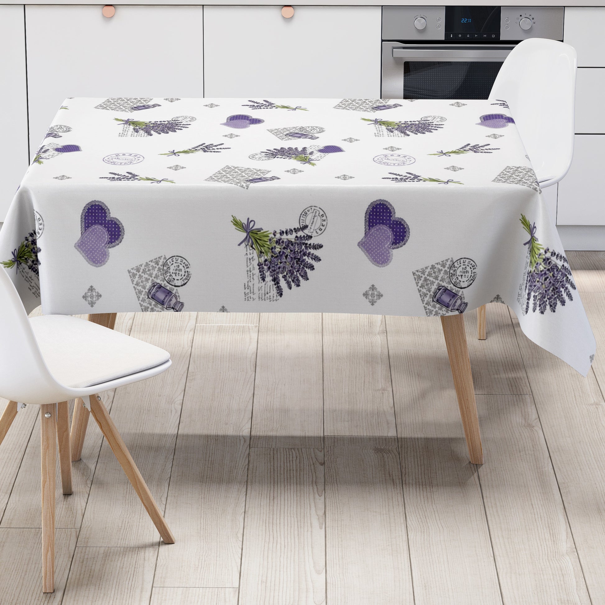 Wachstuch-Tischdecke mit romantischem Lavendel-Motiv auf weißem Hintergrund. Das Design zeigt Lavendelsträuße, lilafarbene Herzen, kleine Lavendelöl-Fläschchen, florale Ornamente und dekorative Vintage-Schriftzüge. Die wasserabweisende Tischdecke fällt gleichmäßig über die Kanten eines rechteckigen Tisches und ist vor weißem Hintergrund freigestellt dargestellt.