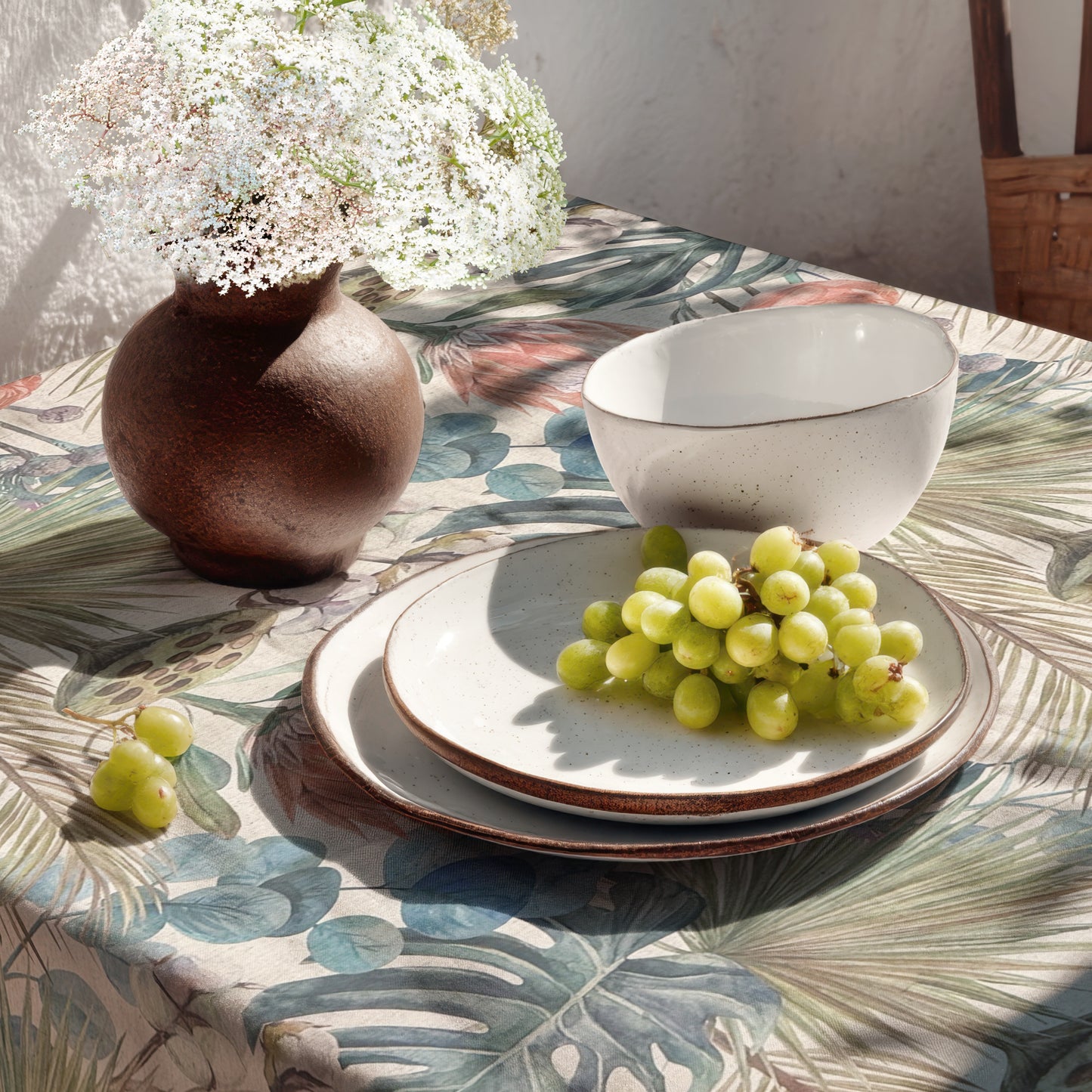 Beschichtete Jacquard-Baumwolltischdecke mit tropischem Pflanzenmotiv aus großen Blättern, exotischen Blüten und botanischen Elementen in Blau-, Grün-, Korall- und Naturtönen, fleckengeschützt und schmutzabweisend.