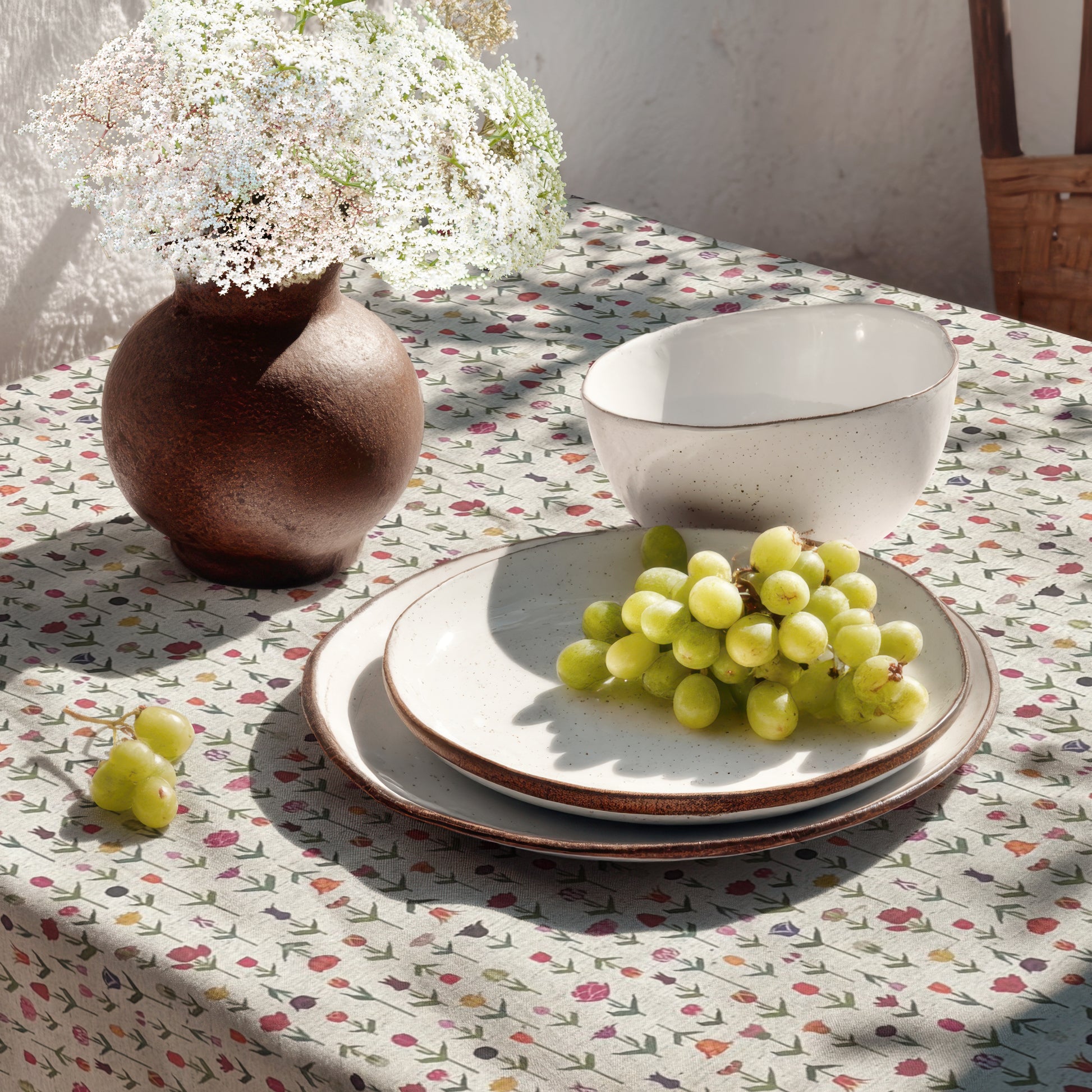 Beschichtete Jacquard-Baumwolltischdecke mit zartem Streublumenmuster aus kleinen bunten Blüten auf naturfarbenem Hintergrund, fleckengeschützt und schmutzabweisend.