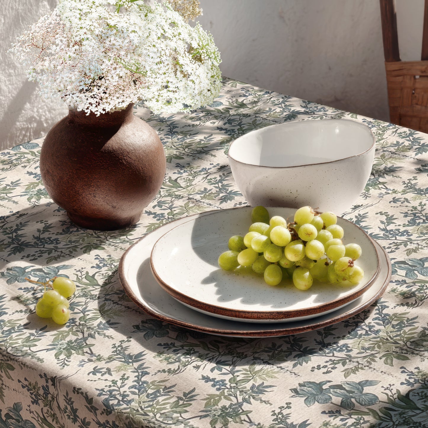 Beschichtete Jacquard-Baumwolltischdecke mit filigranem Blumen- und Blättermuster in Blau- und Grüntönen auf naturfarbenem Hintergrund, fleckengeschützt und schmutzabweisend.