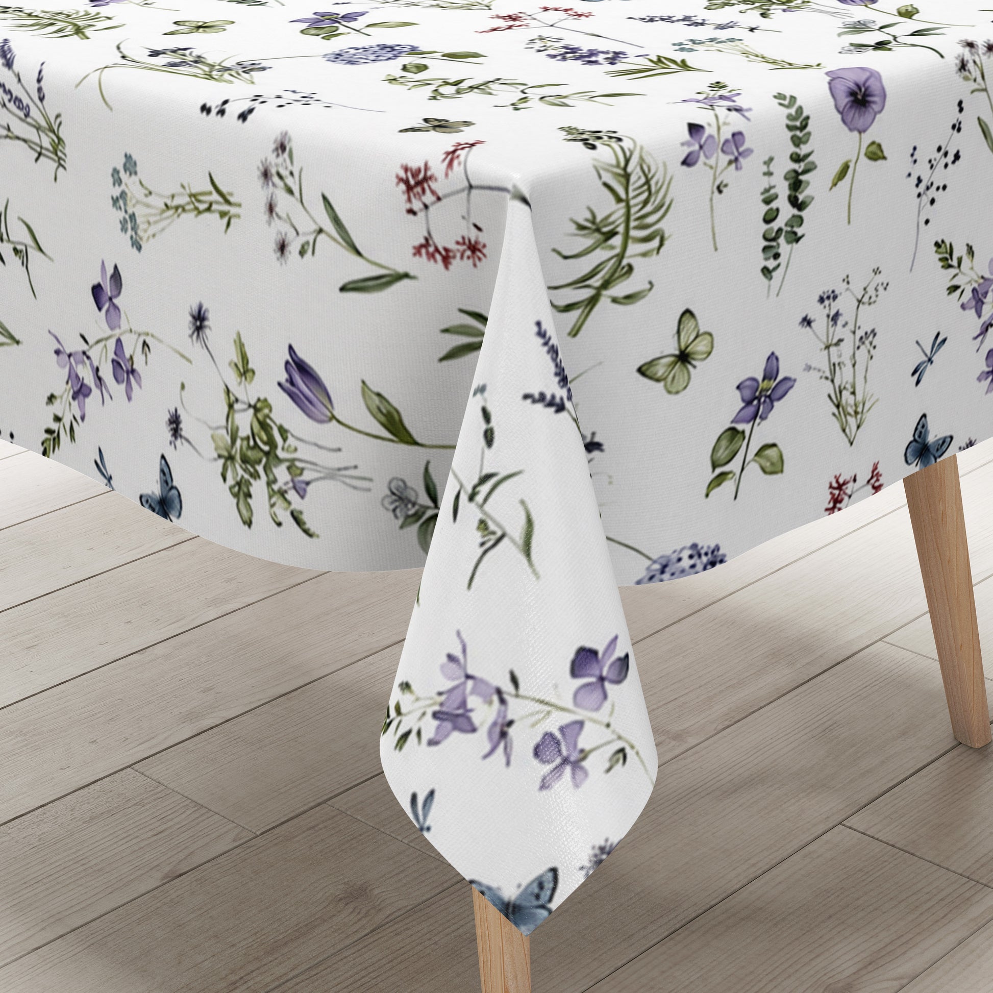 Weiße Wachstuch-Tischdecke mit zartem Wiesenblumen-Muster aus Wildblumen, Gräsern, Schmetterlingen und Libellen in sanften Violett-, Blau- und Grüntönen.