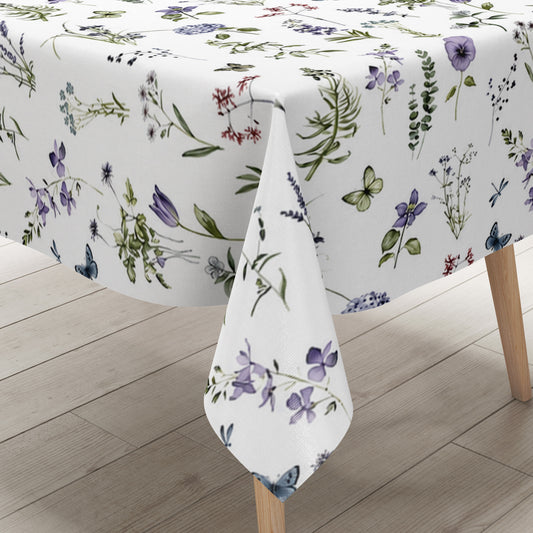 Weiße Wachstuch-Tischdecke mit zartem Wiesenblumen-Muster aus Wildblumen, Gräsern, Schmetterlingen und Libellen in sanften Violett-, Blau- und Grüntönen.
