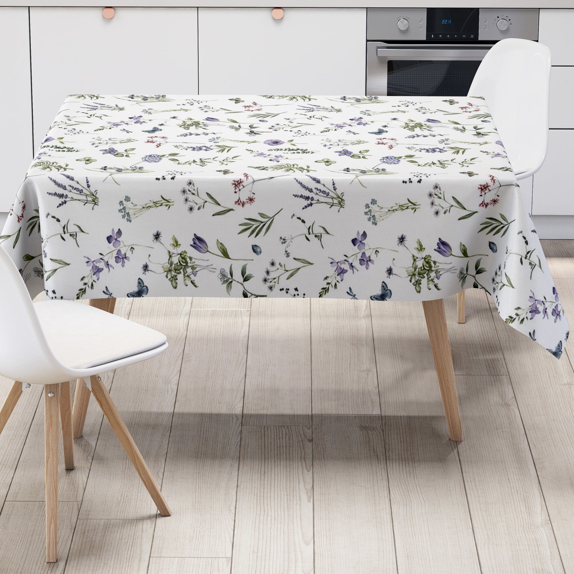 Weiße Wachstuch-Tischdecke mit zartem Wiesenblumen-Muster aus Wildblumen, Gräsern, Schmetterlingen und Libellen in sanften Violett-, Blau- und Grüntönen.