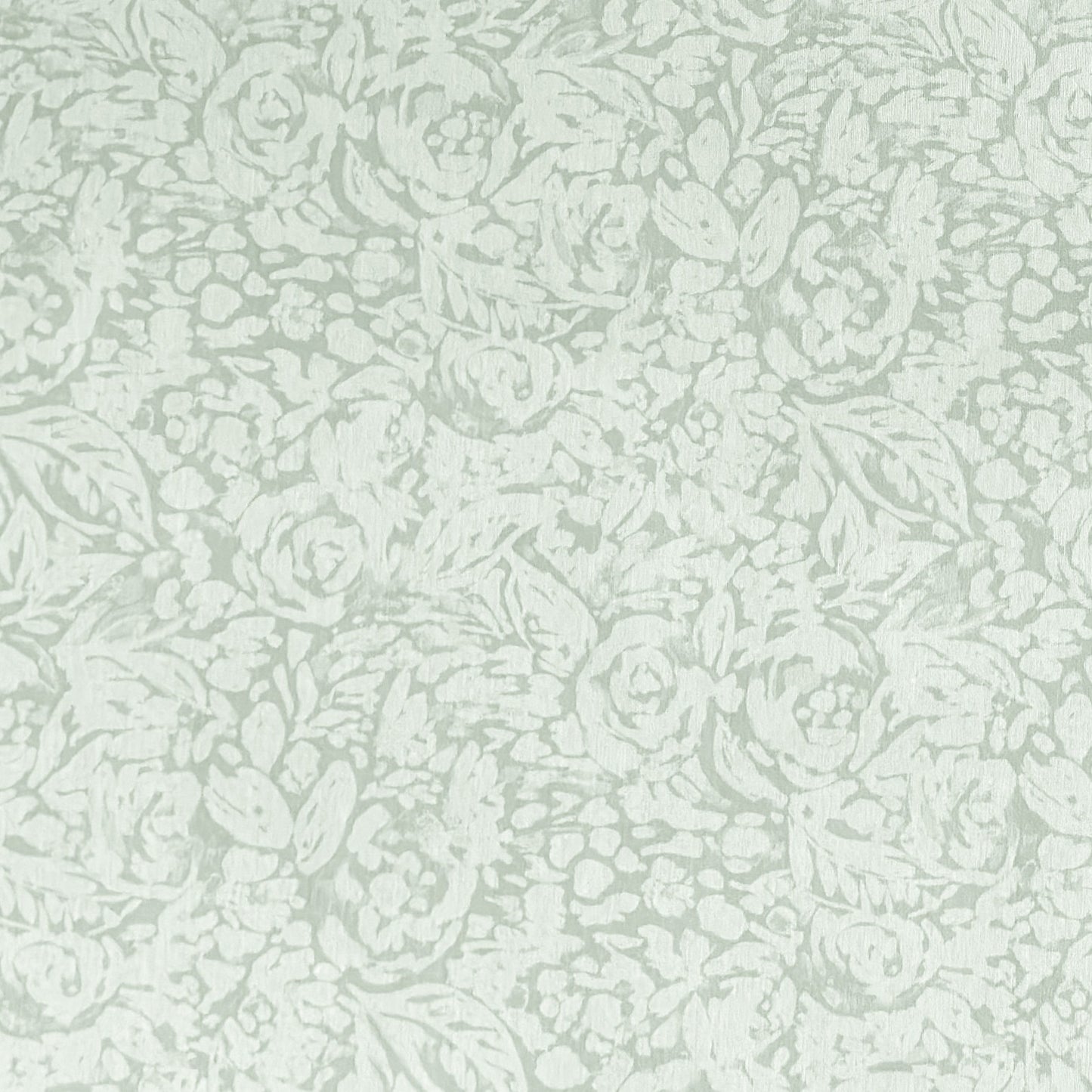 Beschichtete Baumwoll-Tischdecke in hellem Salbeigrün mit floralem Allover-Muster aus Blüten und Blättern auf hellem Hintergrund, über eine Tischecke drapiert. Die matte Oberfläche wirkt pflegeleicht, die Tischbeine aus hellem Holz sind sichtbar.