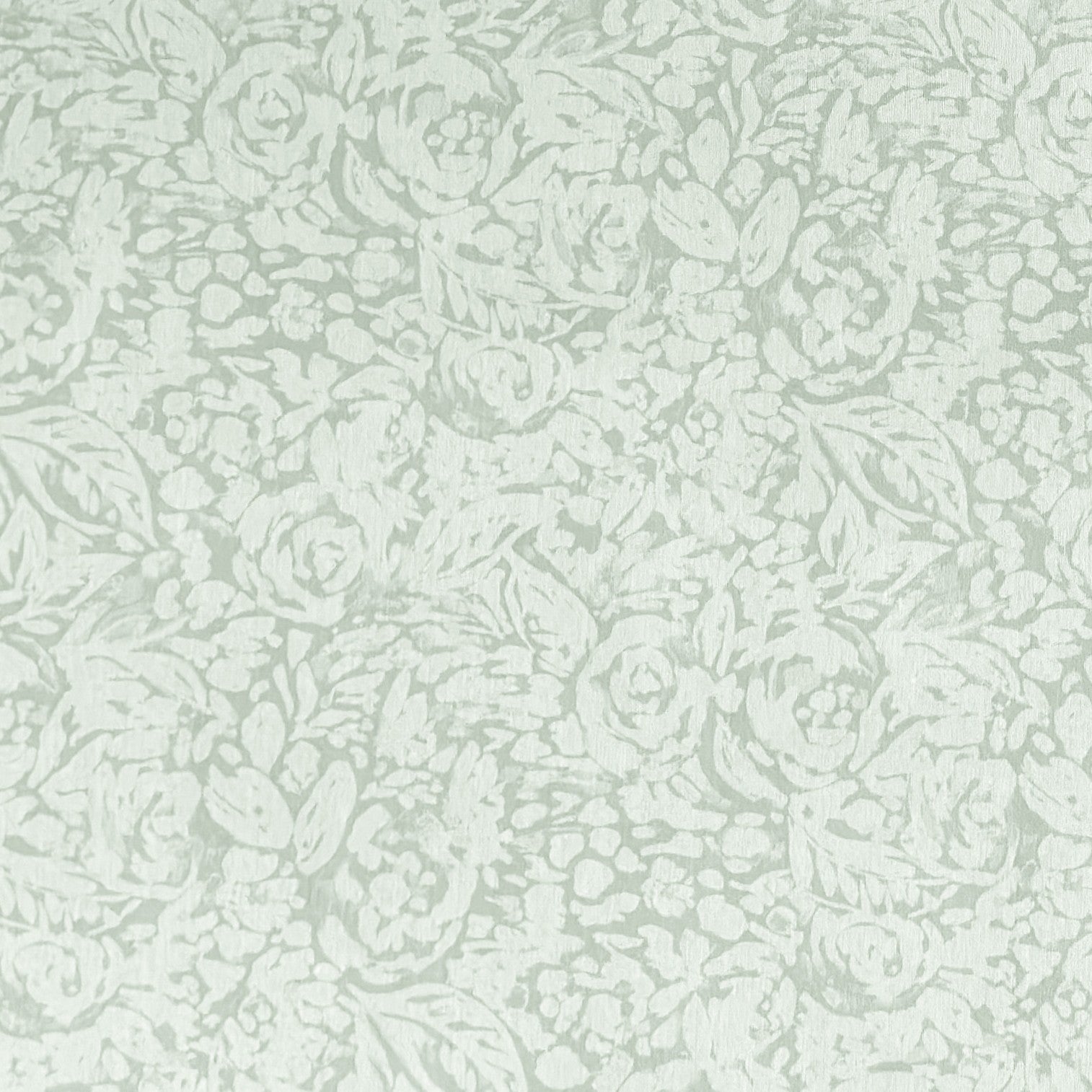 Beschichtete Baumwoll-Tischdecke in hellem Salbeigrün mit floralem Allover-Muster aus Blüten und Blättern auf hellem Hintergrund, über eine Tischecke drapiert. Die matte Oberfläche wirkt pflegeleicht, die Tischbeine aus hellem Holz sind sichtbar.