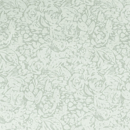 Beschichtete Baumwoll-Tischdecke in hellem Salbeigrün mit floralem Allover-Muster aus Blüten und Blättern auf hellem Hintergrund, über eine Tischecke drapiert. Die matte Oberfläche wirkt pflegeleicht, die Tischbeine aus hellem Holz sind sichtbar.