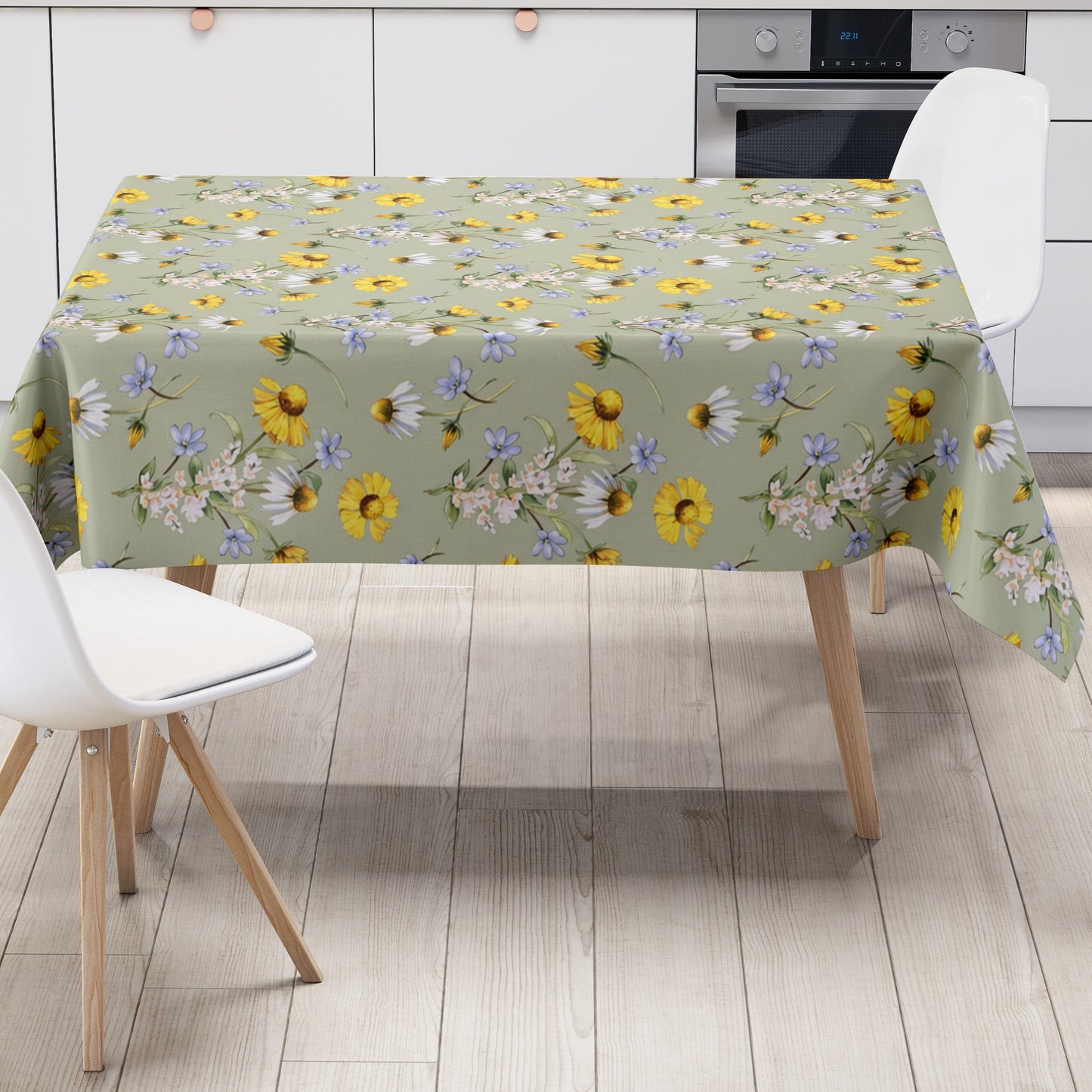Wachstuch-Tischdecke mit Wiesenblumenmuster auf salbeigrünem Hintergrund. Gelbe Blüten, weiße Margeriten, kleine blaue Blumen und zarte weiße Blütenzweige sind gleichmäßig verteilt und sorgen für eine frische, natürliche Ausstrahlung.