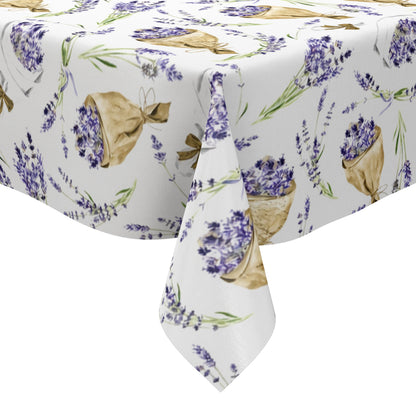 Wachstuch-Tischdecke mit Lavendelmuster auf hellem Hintergrund. Violette Lavendelzweige, kleine Sträuße und in Papier gewickelte Lavendelbouquets sind gleichmäßig verteilt und werden durch grüne Stiele sowie braune Details ergänzt.