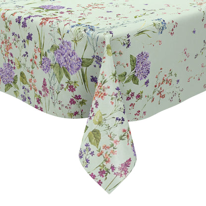 Wachstuchtischdecke mit romantischem Blumenmuster auf mintgrünem Hintergrund. Zarte Wildblumen, filigrane Zweige und Blütenranken in Rosa, Blau, Lila und Rot verteilen sich locker über die Fläche. Große violette Hortensien setzen dekorative Akzente entlang der oberen und unteren Bereiche. Das detailreiche, aquarellartige Dessin wirkt leicht, natürlich und verspielt und verleiht dem Tisch eine frische, florale Ausstrahlung.