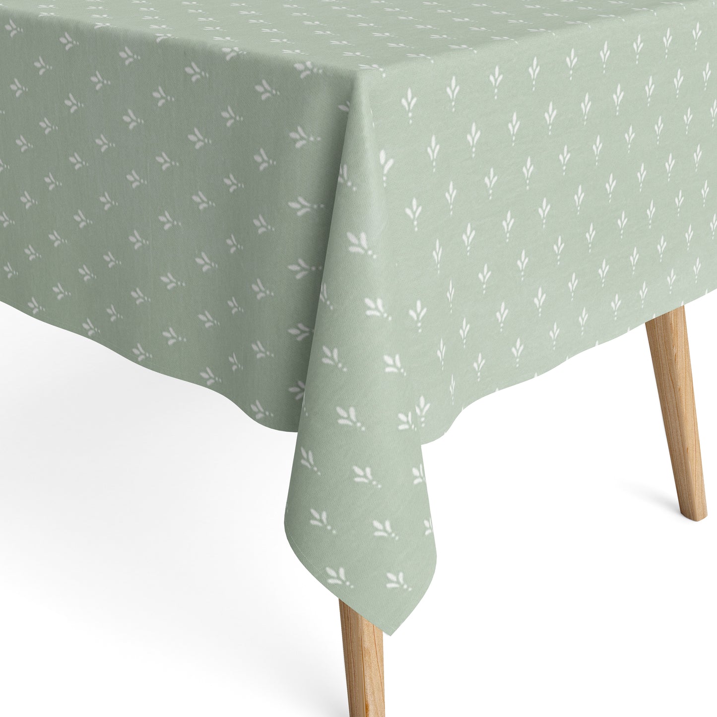 Salbeigrüne Tischdecke aus beschichteter Baumwolle mit Fleckenschutz und kleinen weißen Blattmustern, dekorativ über einem Tisch drapiert.