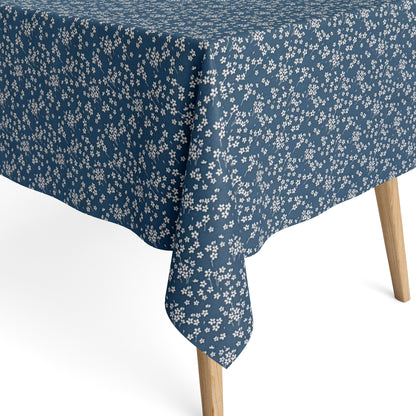 Die Jacquard Tischdecke aus beschichteter Baumwolle zeigt ein dezentes Streublumenmuster mit vielen kleinen, feinen Blüten in Weiß auf dunklem Hintergrund. Die gleichmäßige Verteilung wirkt ruhig und elegant.