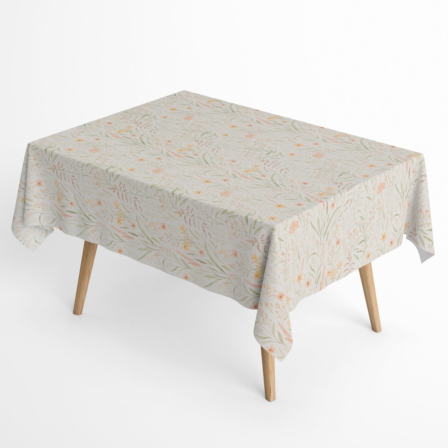 Beschichtete Baumwoll-Tischdecke mit filigranem Naturmuster auf hellem Hintergrund. Zarte Gräser, Blätter und kleine Blüten in Apricot-, Gelb- und Grüntönen verteilen sich gleichmäßig über die Oberfläche. Über eine Tischecke drapiert, mit sichtbaren hellen Holzbeinen.