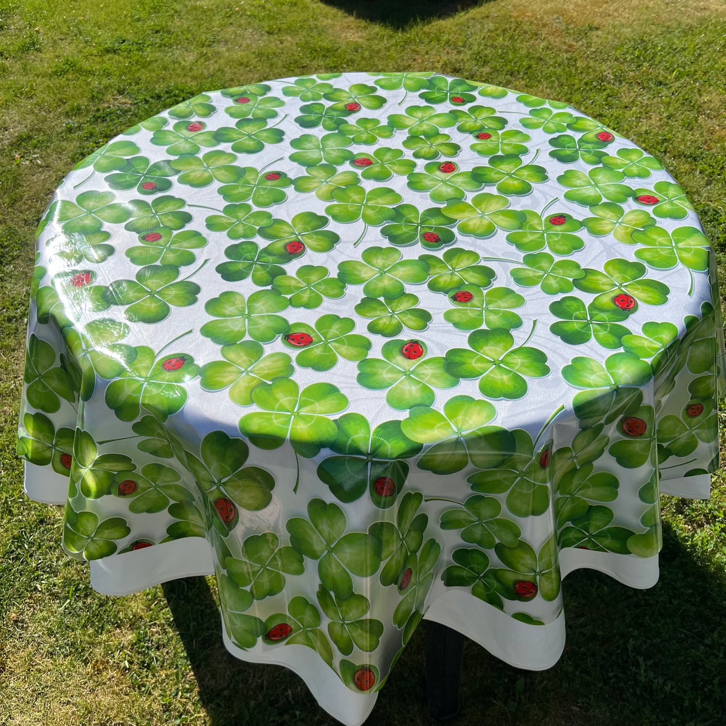 bedruckte Folie mit Klee und Marienkäfer auf einer weißen Stofftischdecke mit floralem Muster fotografiert