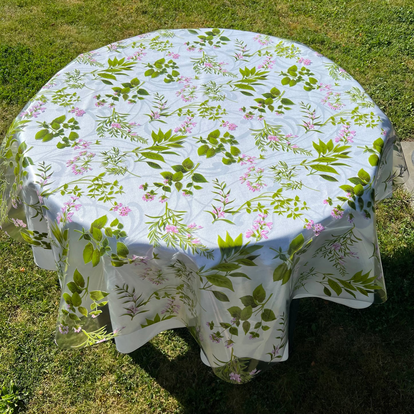 bedruckte Folie mit Kräutern auf einer weißen Stofftischdecke mit floralem Muster fotografiert