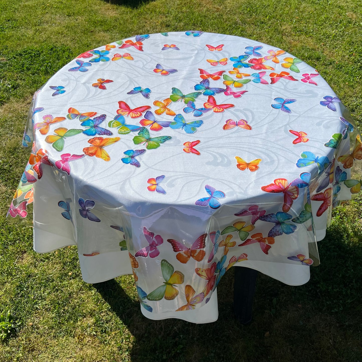 bedruckte Folie mit bunten Schmetterlingen auf einer weißen Stofftischdecke mit floralem Muster fotografiert