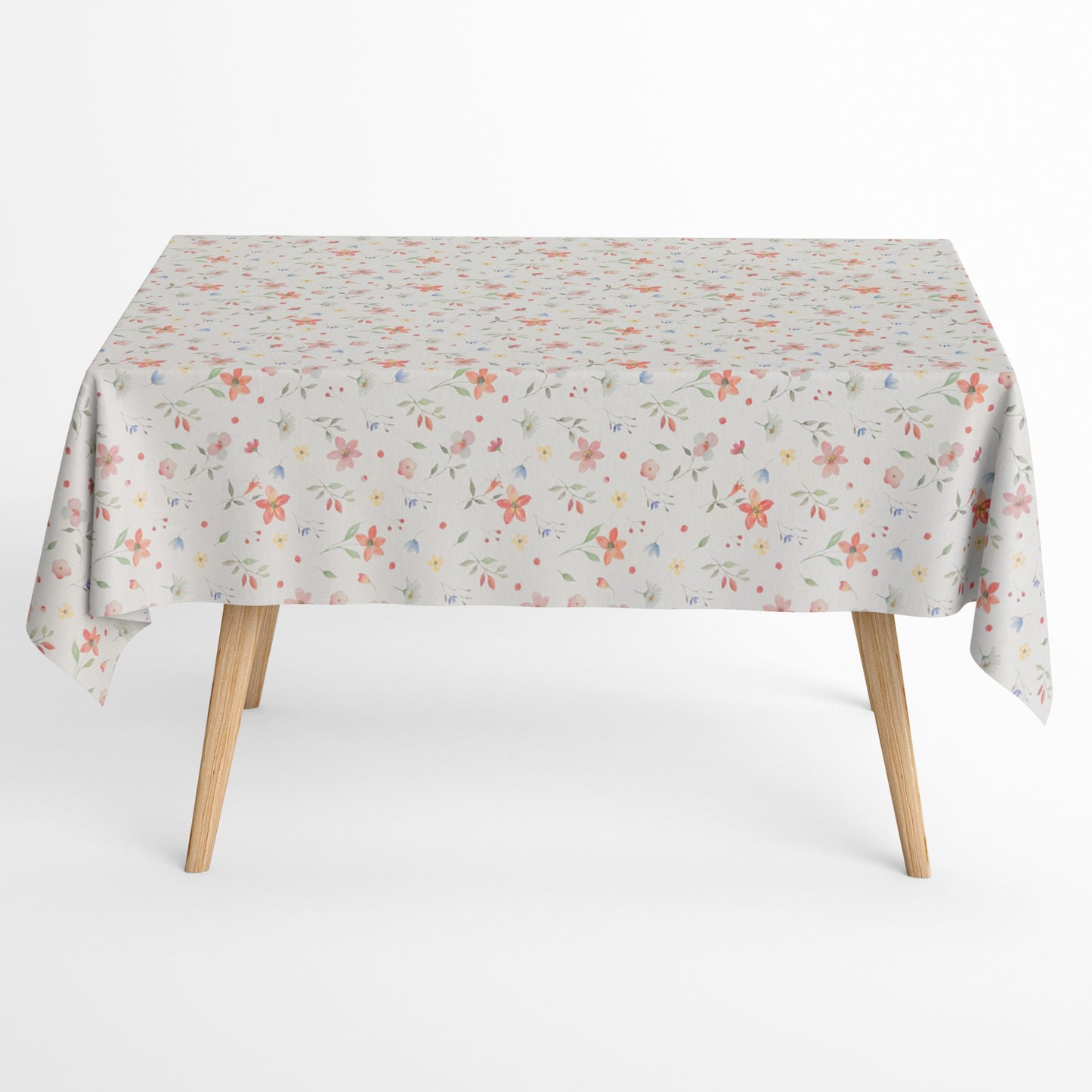 Beschichtete Baumwoll-Tischdecke mit zartem Streublumenmuster auf hellem Hintergrund. Kleine Blüten, feine Zweige und dekorative Punkte in Rosa, Korall, Gelb, Blau und Grün verteilen sich gleichmäßig über die Oberfläche. Über eine Tischecke drapiert, mit sichtbaren hellen Holzbeinen.